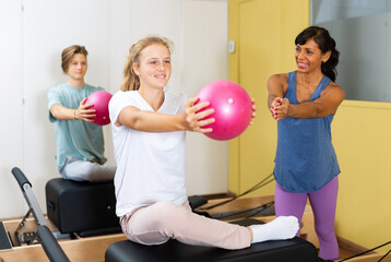 Fototapeta na wymiar Pilates instructor shows girl how to exercise with a ball