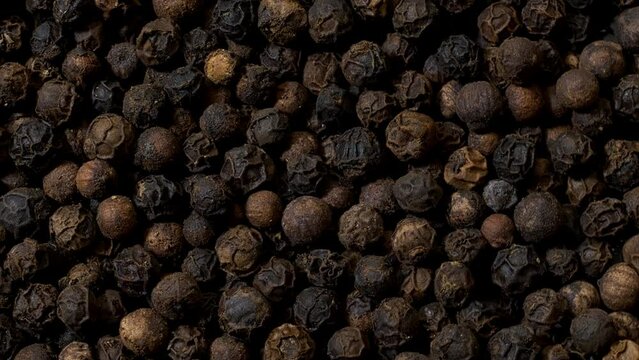 Whole black pepper rotating in a circle as an abstract food texture. Rotation around the lower left corner.