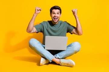 Full length photo of good mood lucky guy wear khaki t-shirt winning game modern gadget isolated yellow color background