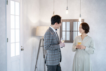 室内でグラスを持ちながら話をする日本人男女
