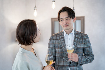 室内でグラスを持ちながら話をする日本人男女