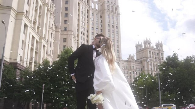 Wedding bliss: Couple's kiss by building, bride in gown, groom in suit.
