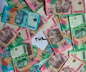 Closeup view of new edition of Indonesian banknotes in a brown envelope for THR (tunjangan hari raya) and salary with white background.
