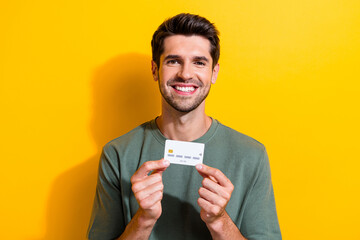 Portrait of toothy beaming guy with stubble wear stylish t-shirt presenting debit card in arms...