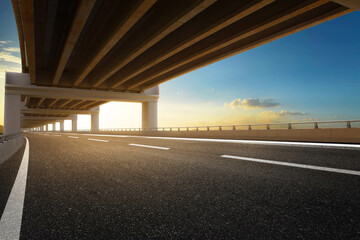 Modern highway road under the overpass with sunset sky.