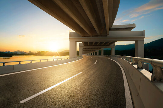 Modern highway road under the overpass with sunset sky.