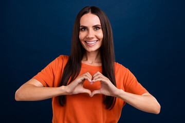 Photo of good mood kind woman with straight hairdo dressed orange t-shirt fingers showing heart...