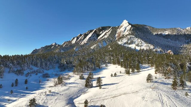 Aerial flyover of  chautauqua park flatirons nature landscape in Boulder, Colorado, USA on a bright winter day with snow covering ground