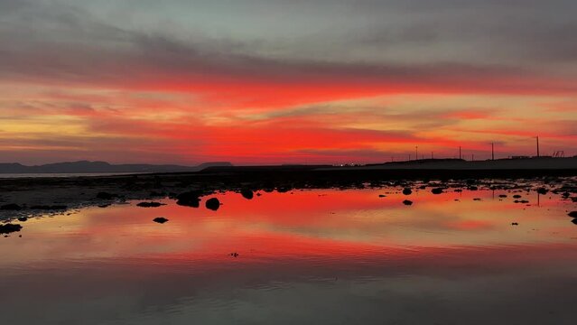 scenic landscape of colorful orange sunset at beach the sand beach seaside rock water pond in tidal time tide move sea level back and low then beautiful landscape reveals in Qeshm Island Iran gulf