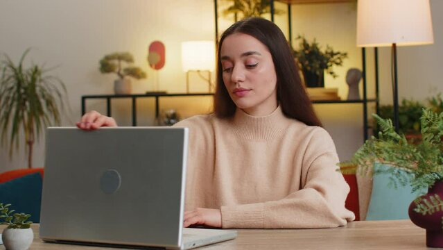 Bored sleepy young woman working on laptop computer leaning on hand falling asleep. Exhausted tired freelancer workaholic female girl sitting at home office at table. Employment, occupation, workless