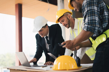 professional engineers in safety vests and hardhats working with blueprints and showing construction, Industrial engineers in hard hat discuss new project, they work in manufacturing factory.