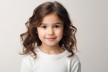 Cute little girl with long curly hair, studio shot over grey background