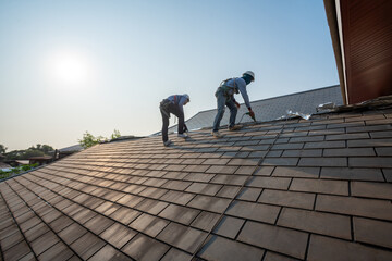 Roofer working in special protective work wear gloves, using air or pneumatic nail gun repair and...