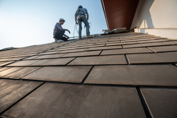 Selective focus of Roof, Roofer worker in special protective work wear and gloves,Using pneumatic...