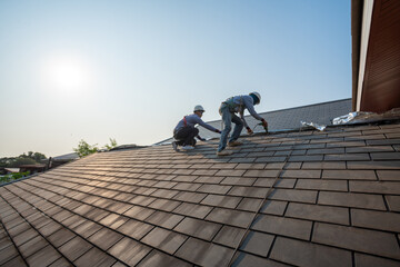 Roofer worker in special protective work wear and gloves,Using pneumatic gun and repair and replace...