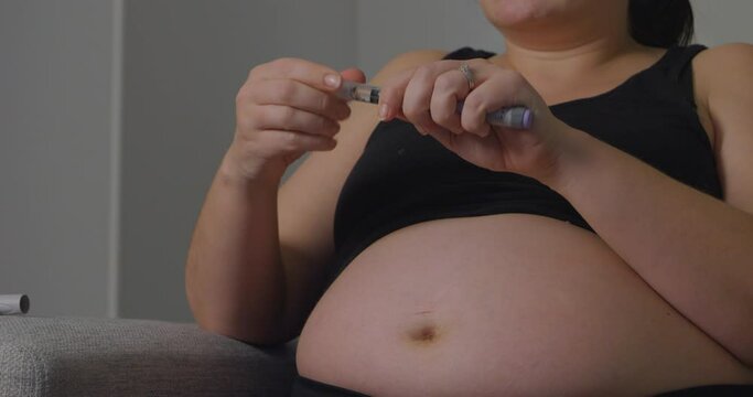 Close up pan right shot of pregnant woman in bra about to apply insulin