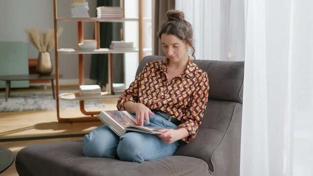 Woman sits in modern living room and flips through coffee table book