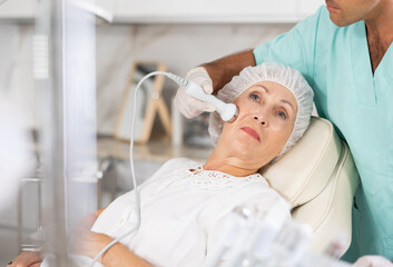 Using ultrasonic import, male physician enhances woman's features through tailored procedures.