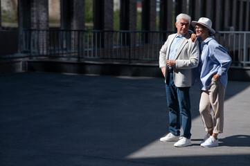 Stylish mature couple. Gray-haired man and woman holding hands while walking around the city. 
