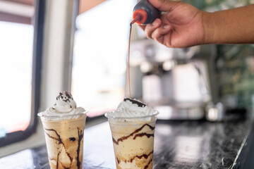 Barista garnishing a iced coffee with cream and caramel