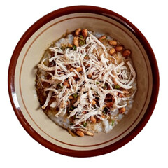 Bubur ayam or chicken congee is Chinese Indonesian rice porridge topped with shredded chicken and various savoury condiments served on bowl and isolated on white background.