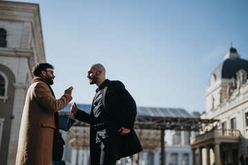 Captured in natural daylight, two professional men are seen sharing a convivial chat, with one...