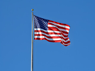 American flag waving proudly against a blue sky with stars and stripes, symbolizing freedom and patriotism in the United States