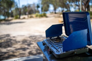 Cooking on a gas cooker at a campsite in the Forrest. Cooking outside on a blue camper trailer. Having fun in a tent in the bush in a national park in Sydney, nsw, Australia.