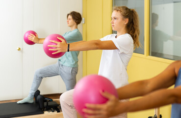 Teen girl holding a ball in pilates class in gym