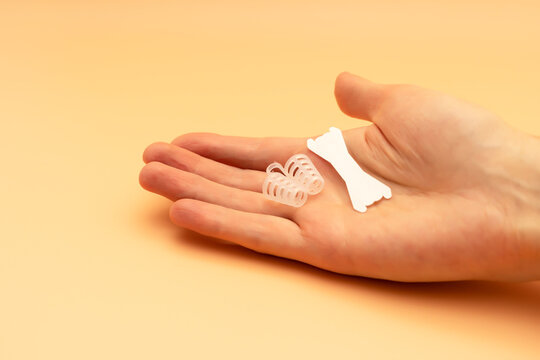 Anti Snoring Device in Human Hand. Nose Relief Nasal Dilator, White Nasal Strip on Peach Yellow Background, Sleeping Apnea Solution for Nasal Breathers, Snoring Problem. Space For Text Horizontal.