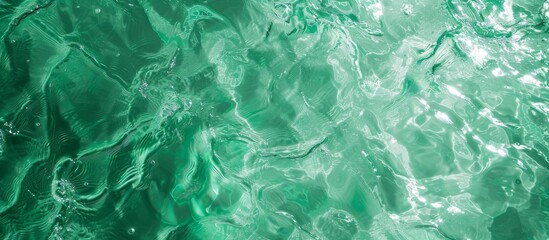 Top view of green water with natural sunlight shapes, creating an abstract crystal clear texture background and free space for designers.