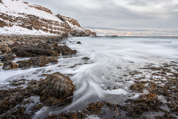 Water flowing over the rock on the shore of the Varangerfjorden on a cold winter day during the polar night, Northern Norway