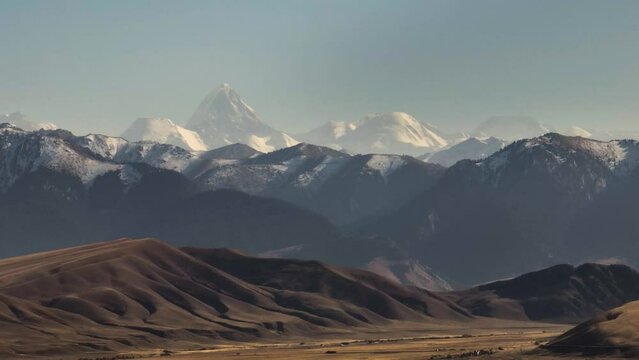 Mountainous terrain with beautiful skin rocky slopes with snow peaks background. Martian plateau landscape in Kazakhstan at summer sunny sunset.