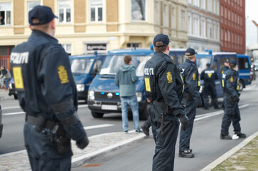 Police officer, group and patrol in street for crowd safety with protection service for public in city. People, law enforcement and justice in danger, arrest or warning on urban road in Copenhagen