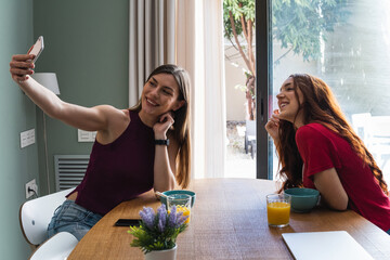 Happy friends taking selfie with mobile smartphone while lunching at home - Young trendy woman...