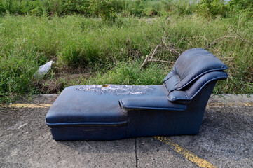 Closeup of Dirty Old Black Tone Sofa left in the forest on the side of the road, Selective Focus.