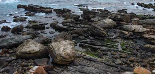 Amazing rocks laying on the coastline, splashed by the ocean, in Keelung city, Taiwan.