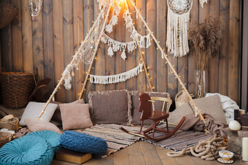 Wooden rustic interior background with decorative pillows and a wooden horse swing.