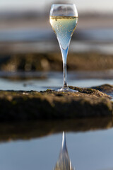 A glass of champagne or cava on vacation, low tide on Dunes Corralejo sandy beach, Fuerteventura, Canary islands