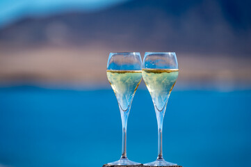 Pouring a glass of champagne on vacation, south of Fuerteventura, Canary islands, blue ocean, mountains