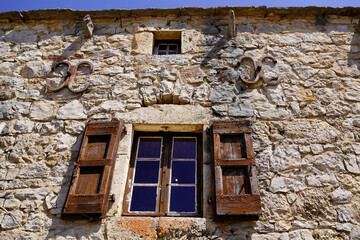 old house facade with typical stone wall and window, classic wooden shutters and metal reinforcement from the center of France in Lozere France