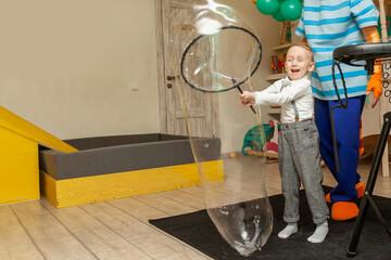 A little boy plays with big soap bubbles at a birthday party with an animator.