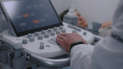 Close up of doctor using sonography machine with digital monitor. Medical specialist does ultrasound diagnostic to pregnant female patient. Modern clinic or medical center with advanced equipment.