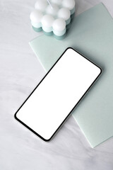 Mobile phone with blank screen mockup, pastel sage green paper stationery, candle on marble desk background, aesthetic minimal fresh spring business branding template, flat lay