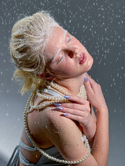 Portrait of a blonde girl in snowflakes. Photo in the studio.