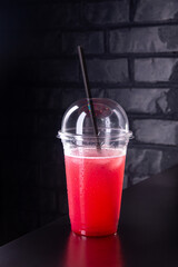 Red lemonade with ice cubes in a plastic glass