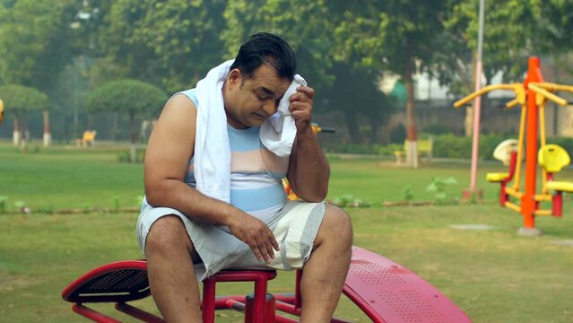 Portrait of Overweight man getting tired - weight loss  fat loss  healthy lifestyle  excessive sweat. Indian obese man wiping his sweat with a towel after exercising - health care  weight loss thro...