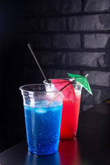 Red and blue lemonade with ice cubes in a plastic glasses