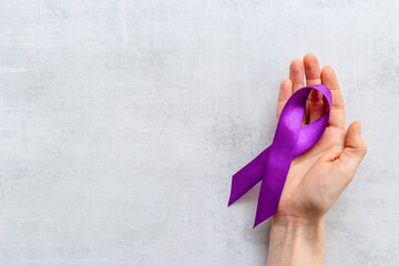 Purple ribbon symbol of pancreas cancer and Alzheimer's disease with hands. Medical support concept