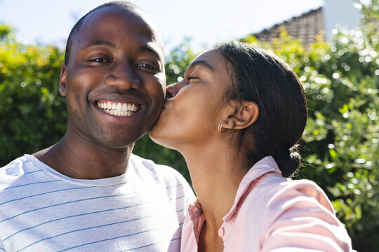 Young African American man receives a kiss on the cheek from a biracial woman